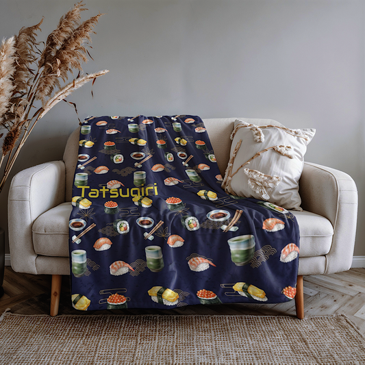 Navy blue personalised throw blanket with sushi pattern draped over a beige sofa in a living room.